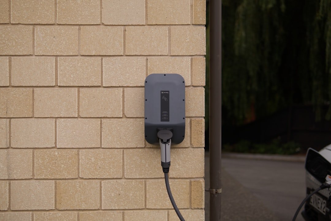 Level 2 EV charger mounted on an exterior brick wall by Geib's Electric
